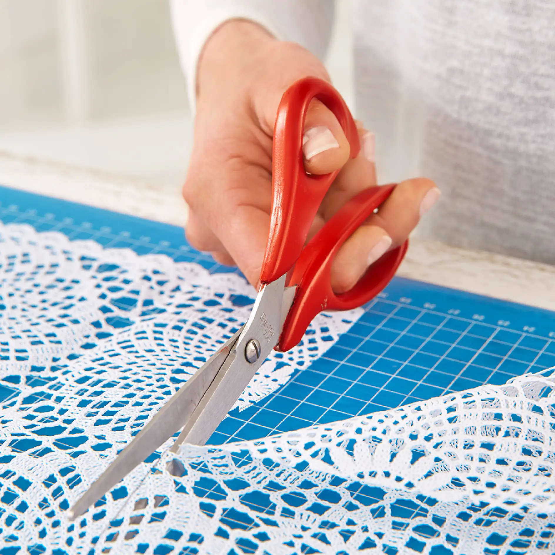 Cutting out the DIY lace window treatment with scissors