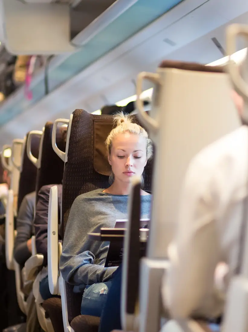 Wanita kulit putih pirang sederhana bepergian dengan kereta. Kereta yang penuh dengan penumpang angkutan umum pada jam sibuk untuk berangkat kerja. Gambar Adobe Stock