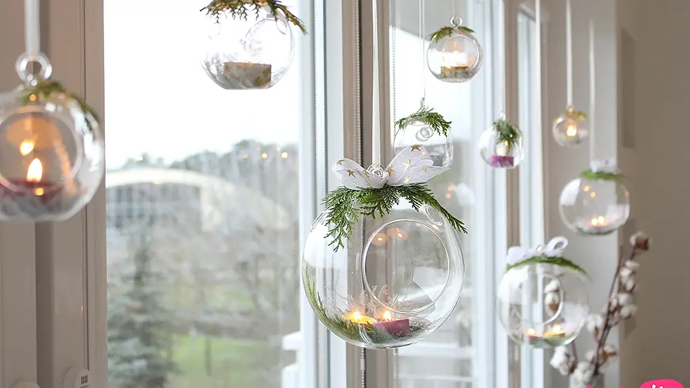 Wiszące szklane lampiony na świece w świątecznym oknie