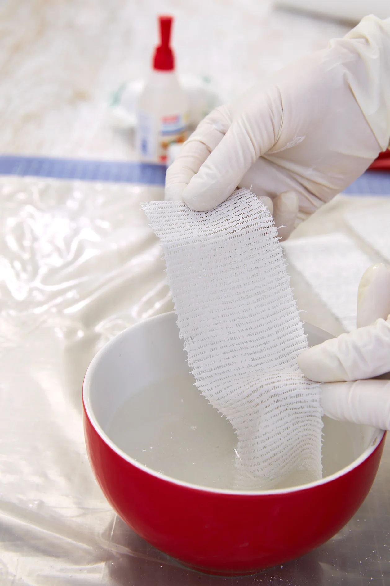 Briefly dip the plaster bandages into cold water.