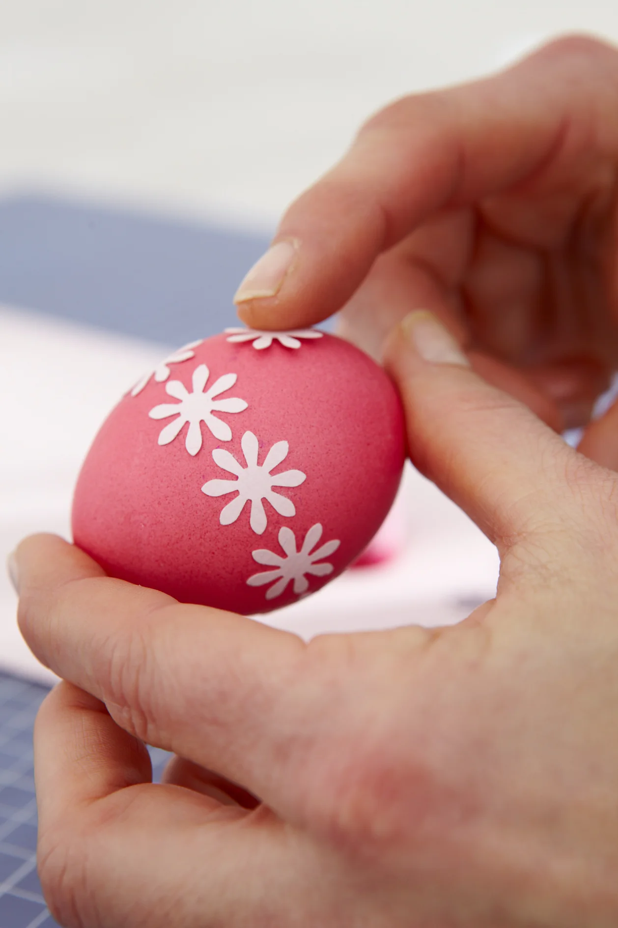 Papierblüten in unterschiedlichen Mustern auf die gefärbten Eier kleben.
