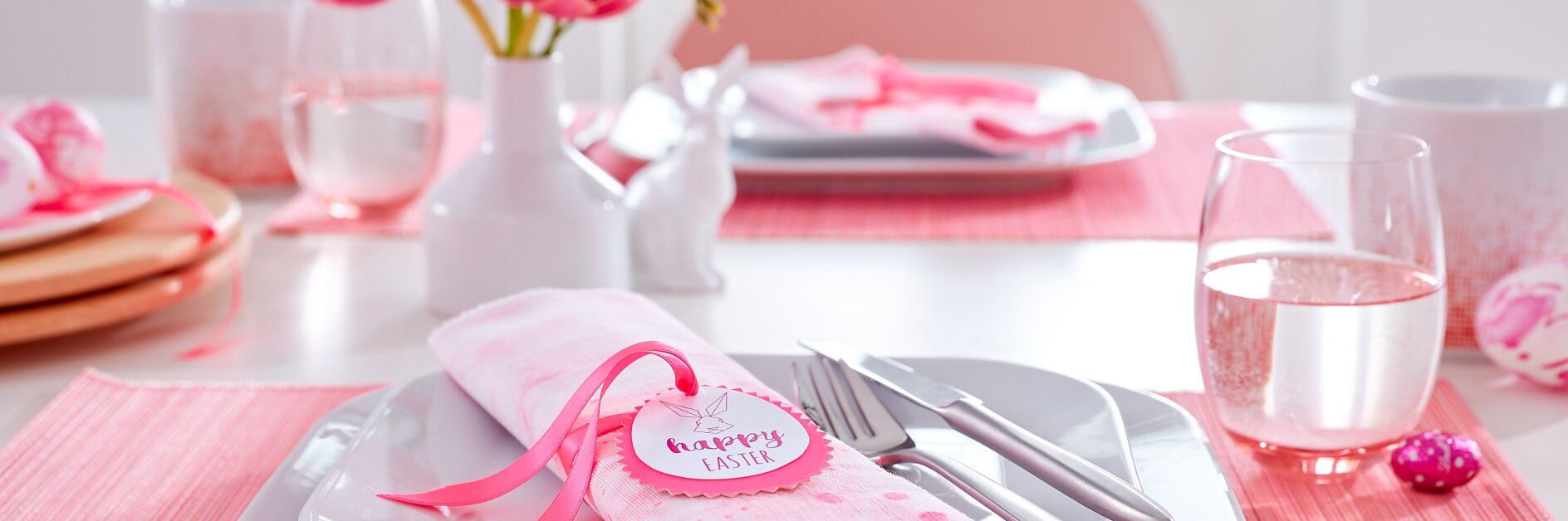 Pink is the main color on this Easter table. The bunny napkin folds each wear a matching DIY napkin ring with a bunny portrait and good wishes for the spring holidays.