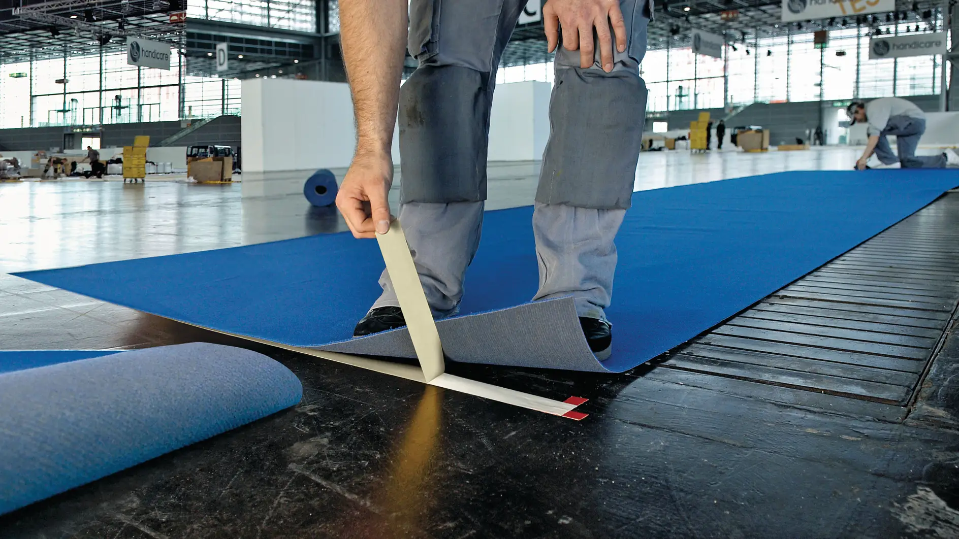 Professionelle håndværkere, der bruger dobbeltsidet gulvtape til fastgørelse af tæppe