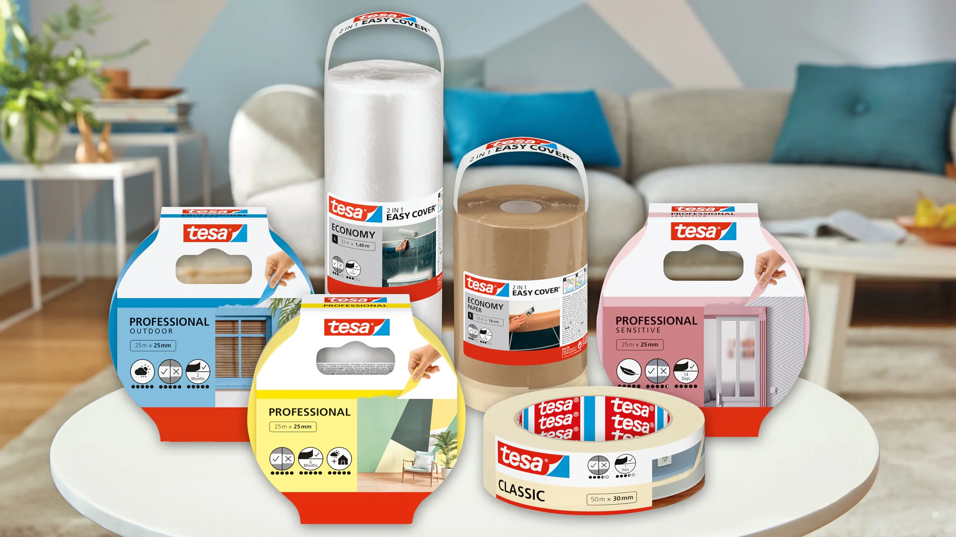 En række forskellige tesa tape-produkter vises på et bord. Emballagen er farverig og byder på forskellige typer til professionel og hjemmebrug, inklusive udendørs, indendørs og klassiske muligheder. En sofa og indretning kan ses i den slørede baggrund. (This text has been generated by AI)