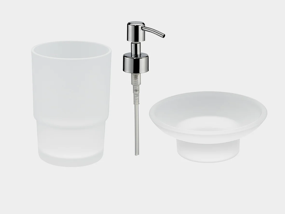 Et sæt minimalistisk badeværelsestilbehør på en ensfarvet baggrund. Indeholder en tumbler i matteret glas, en sæbedispenser med en pumpe i krom og en lav skål i matteret glas. (This text has been generated by AI)