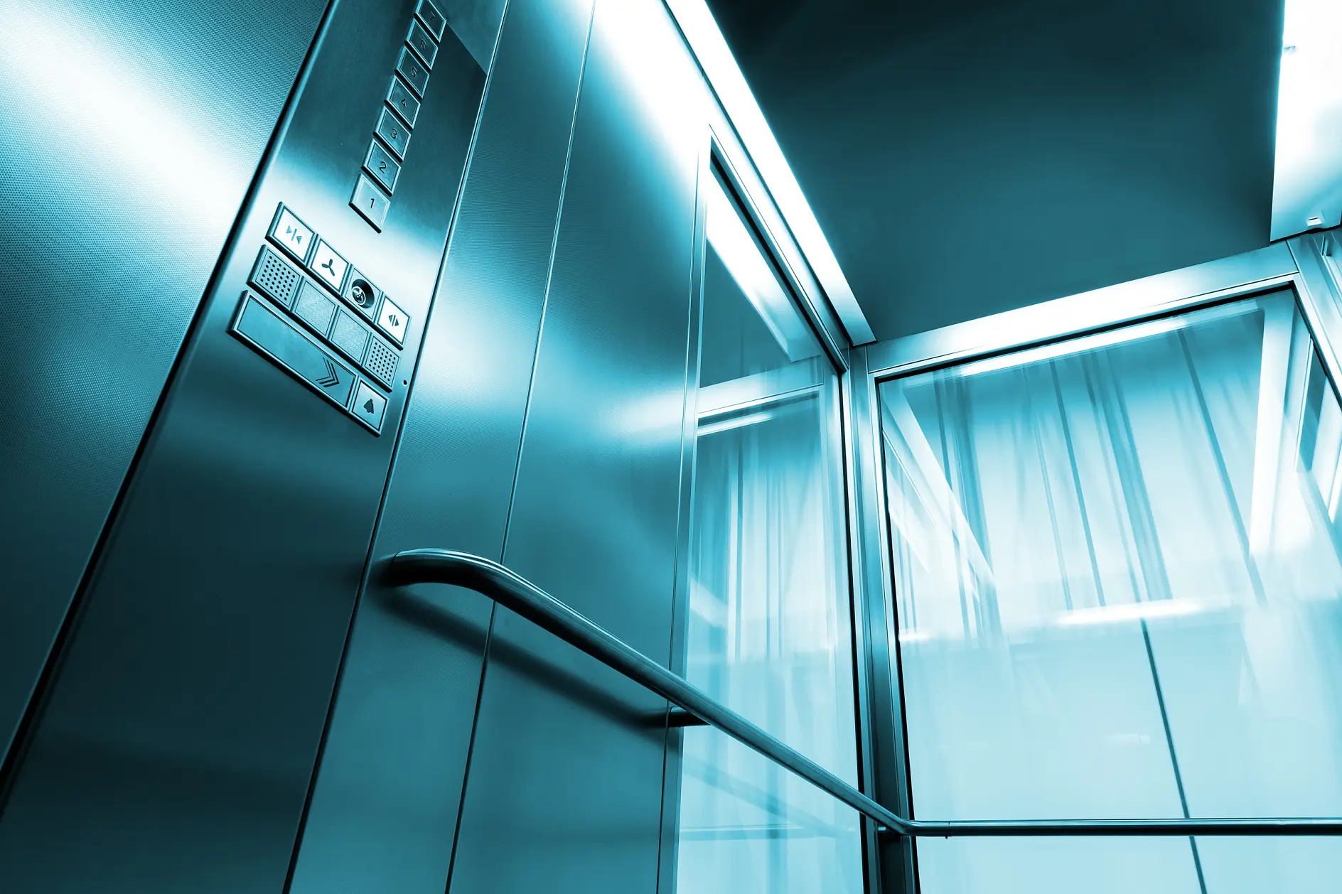 Inde i en elevator af metal og glas i en moderne bygning, de skinnende knapgelændere