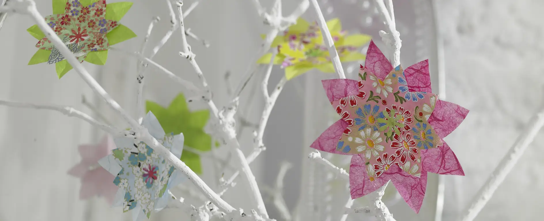 Bunte Blumen im Origami-Stil lassen die weißen Zweige aufblühen.