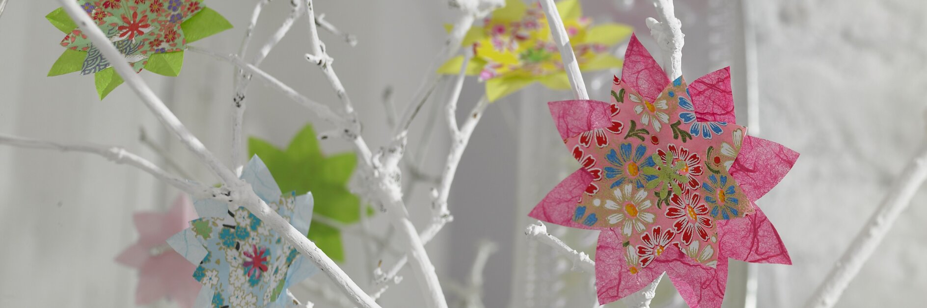 Bunte Blumen im Origami-Stil lassen die weißen Zweige aufblühen.