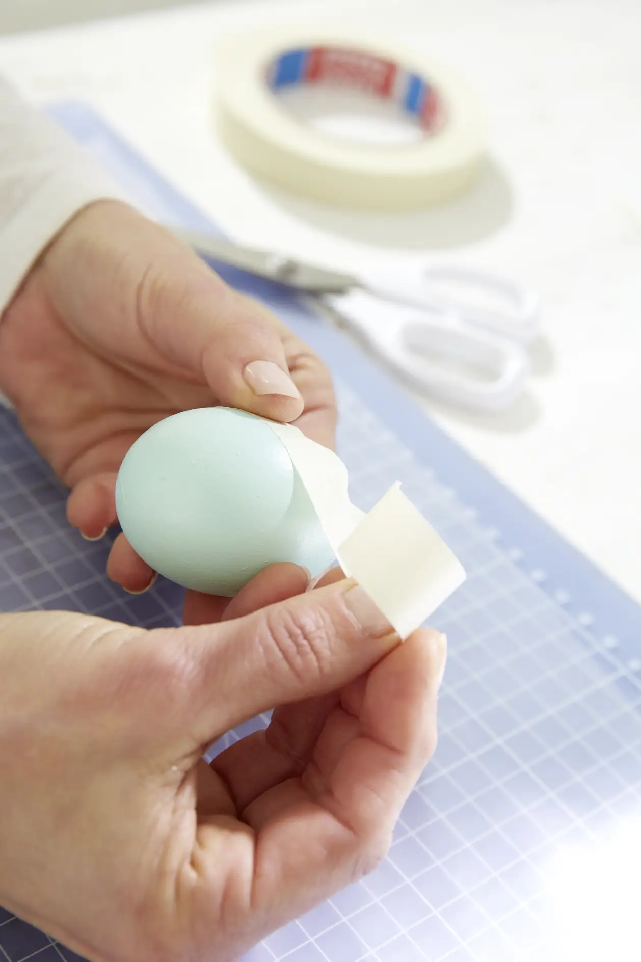 Eine Fläche mit dem tesa® Malerband CLASSIC auf dem Ei abkleben.
