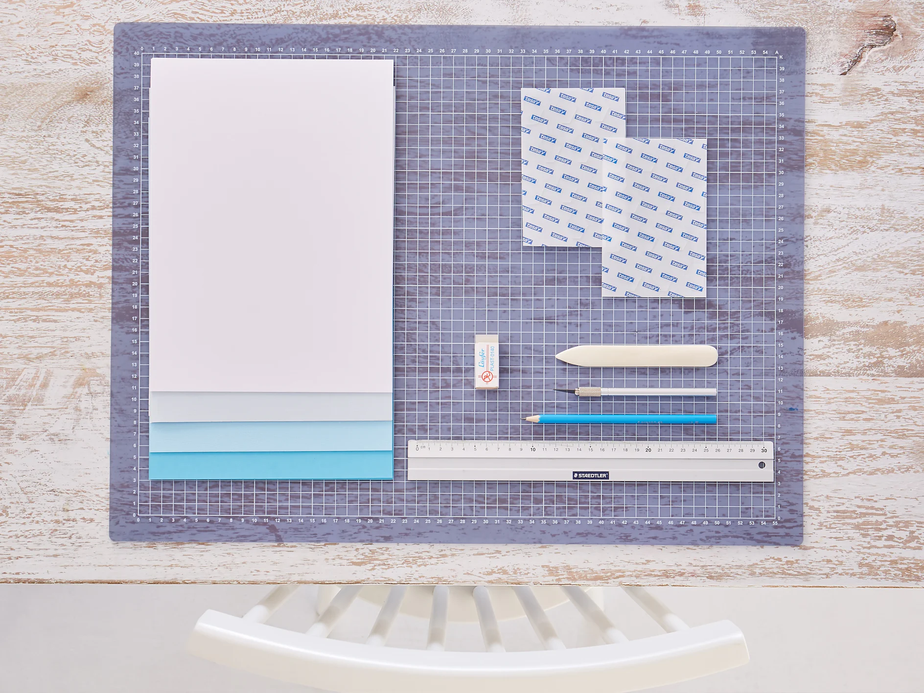 tesa trendpapier 24 / Idee 1: Wandbild / Schritt 1 Das brauchen wir: DIN-A-4-Karton in abgestuften Blautönen und Weiß, Lineal, Cutter, Bleistift, Falzbein, Radiergummi, Schneideunterlage, tesa® TACK Transparente Doppelseitige Klebepads XL