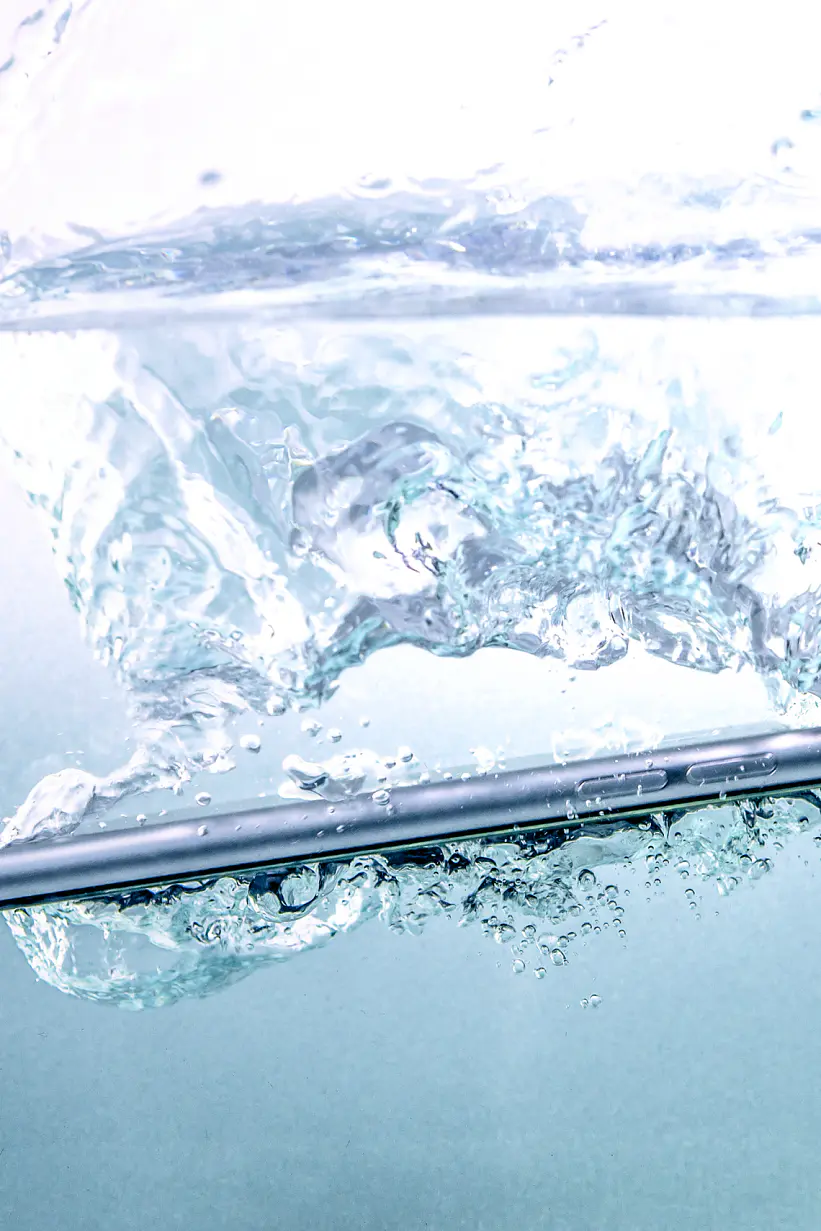 A smartphone submerged in water, creating bubbles and ripples in the surrounding liquid, is secured with tesa tape. (This text has been generated by AI)