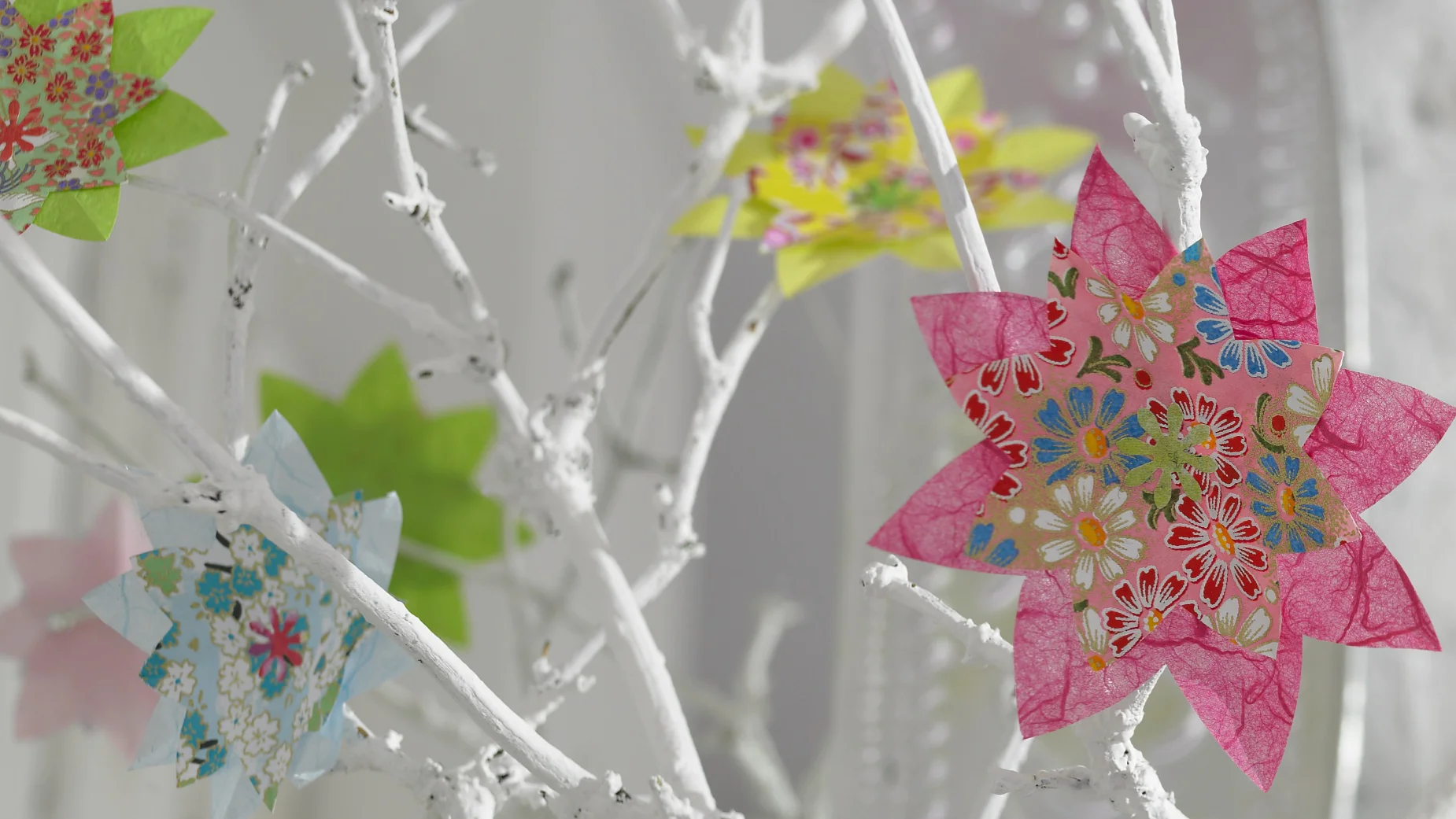 Bunte Blumen im Origami-Stil lassen die weißen Zweige aufblühen.