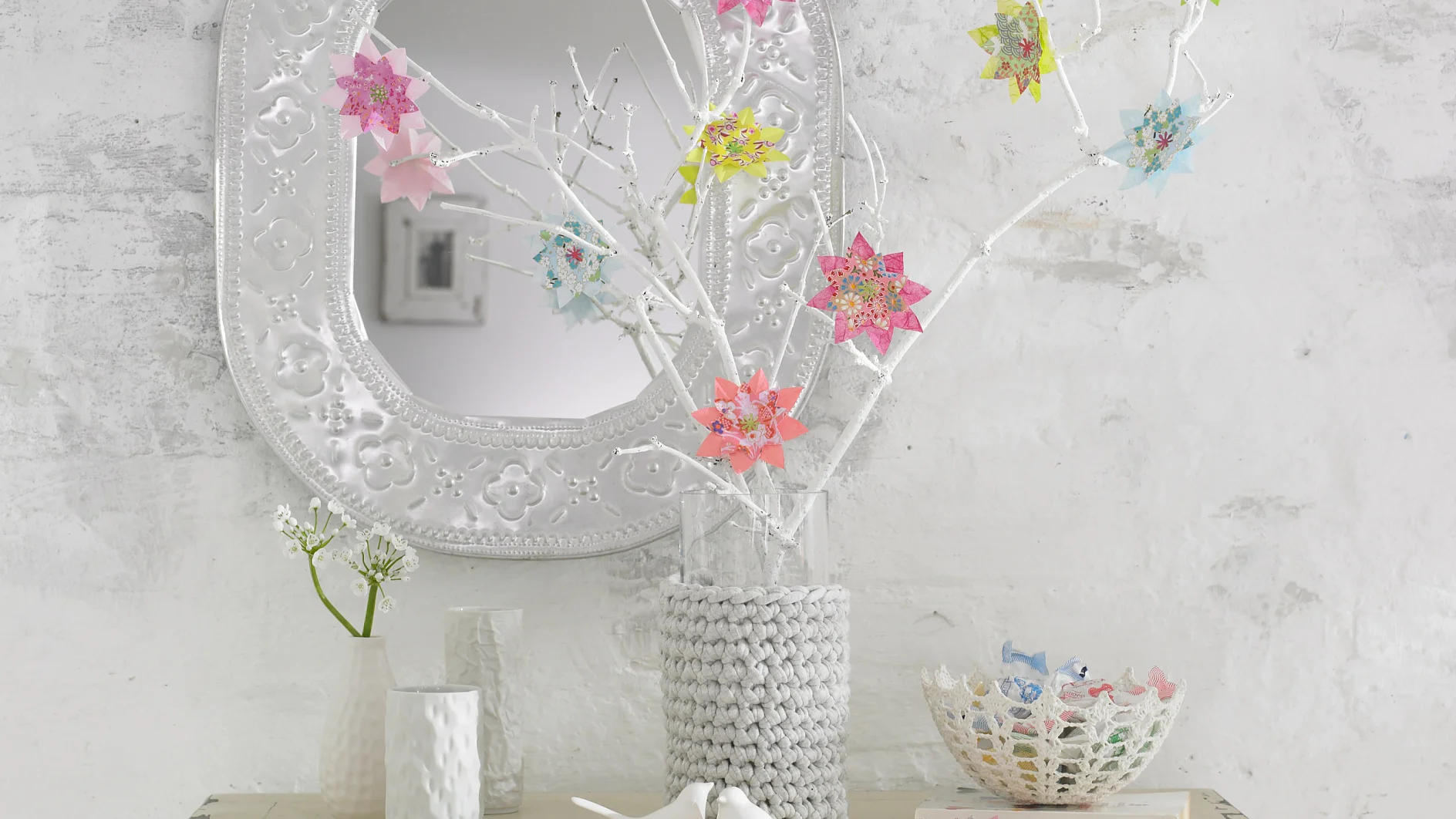 Bunte Blumen im Origami-Stil lassen die weißen Zweige aufblühen.