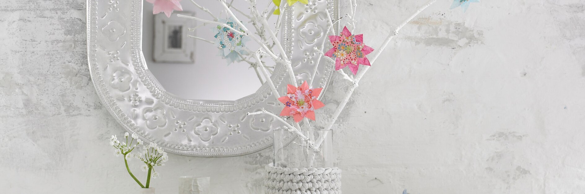 Bunte Blumen im Origami-Stil lassen die weißen Zweige aufblühen.