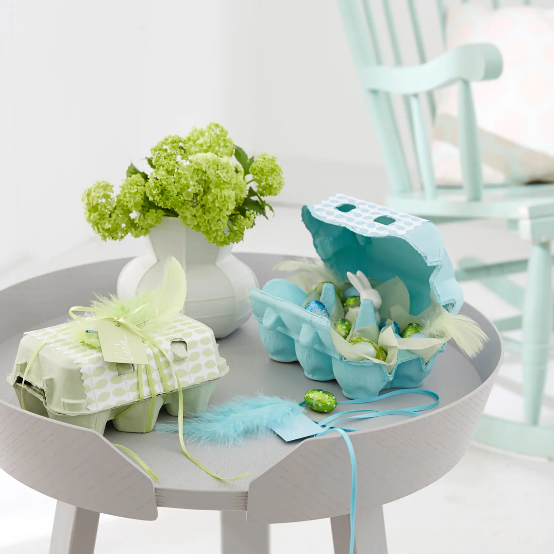 Aus einem Eierkarton kann ein süßes Osternest werden, dem man die Wiederverwertung nicht ansieht: Banderole schnippeln, aufkleben, mit Federn und Namensschild verzieren – fertig!