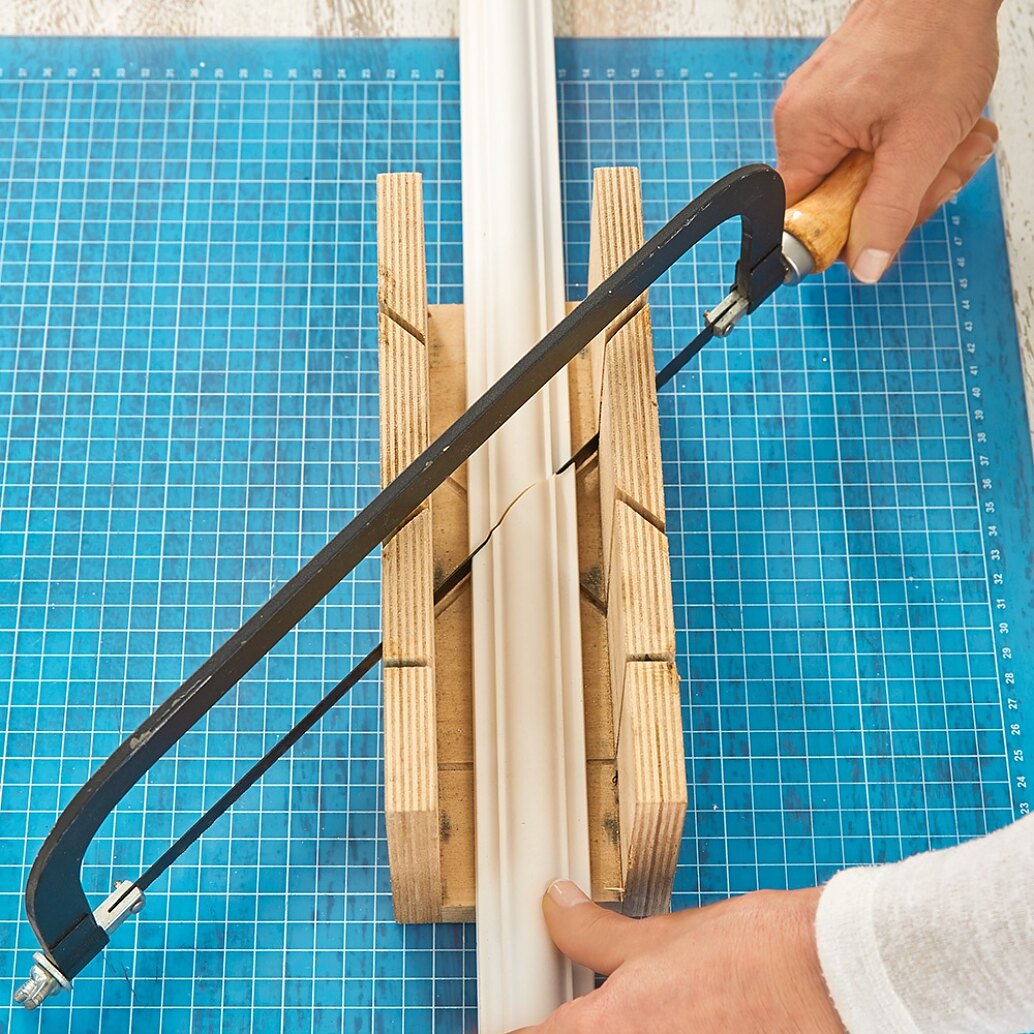 Sawing lengths of decorative plasterwork while making a DIY headboard. Entwerfen Sie Ihr Design.