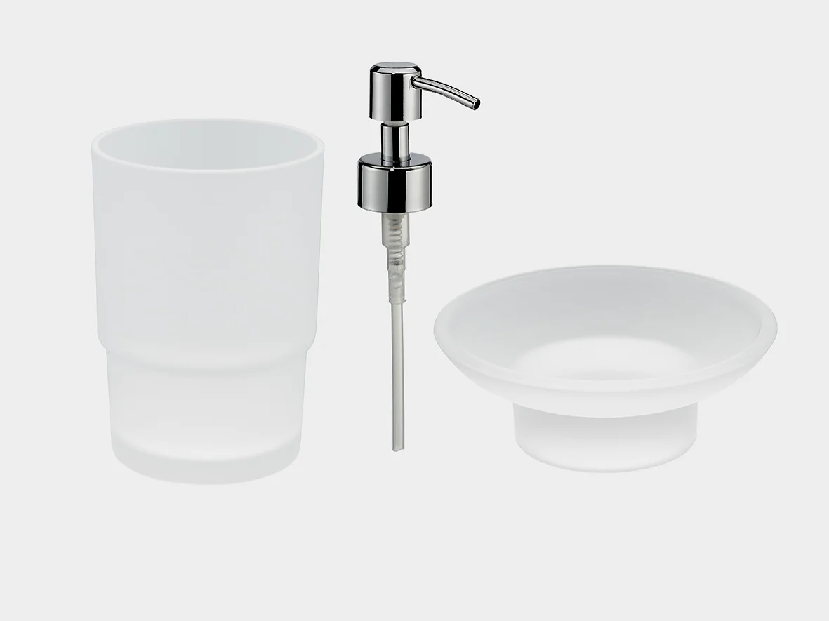A set of minimalist bathroom accessories on a plain background. Includes a frosted glass tumbler, a soap dispenser with a chrome pump, and a shallow frosted glass dish. (This text has been generated by AI)