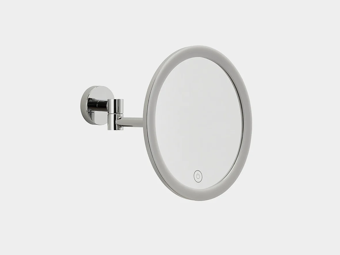 A round wall-mounted mirror with a chrome frame and adjustable arm. The mirror features a circular touch-sensitive button on its lower edge, indicating an LED light feature. The background is plain white. (This text has been generated by AI)