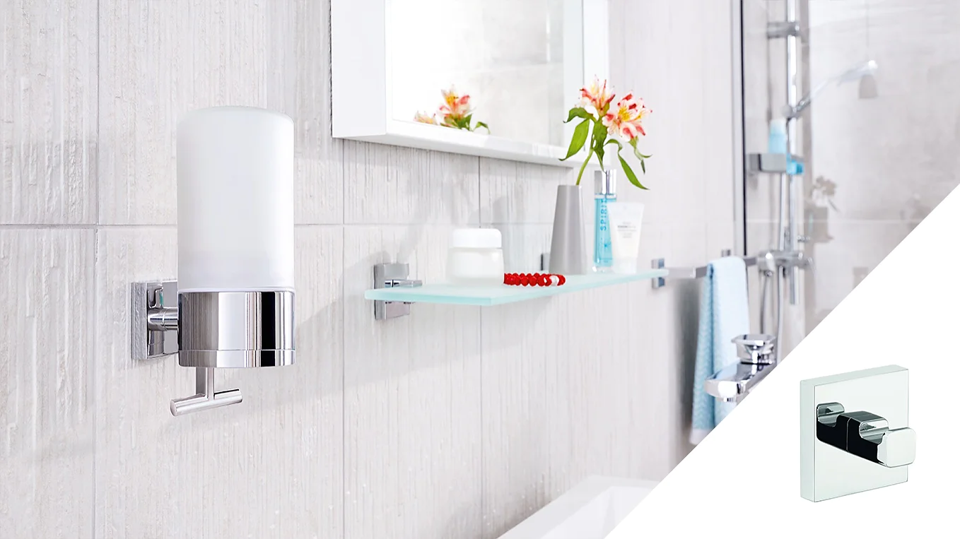 A modern bathroom features a wall-mounted soap dispenser and a glass shelf with toiletries, including a toothbrush, a small container, and a bottle with flowers. The decor includes neutral tiles and a mirror, with a shower visible in the background. All these elements are secured using tesa tape for added stability and style. (This text has been generated by AI)