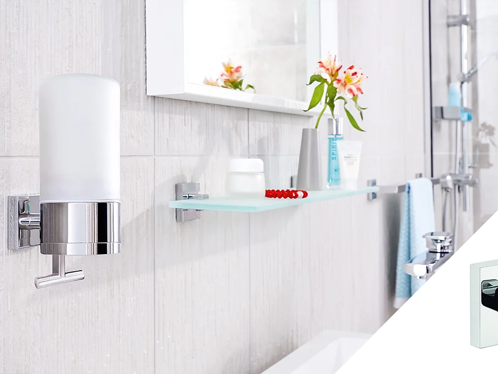 A modern bathroom features a wall-mounted soap dispenser and a glass shelf with toiletries, including a toothbrush, a small container, and a bottle with flowers. The decor includes neutral tiles and a mirror, with a shower visible in the background. All these elements are secured using tesa tape for added stability and style. (This text has been generated by AI)