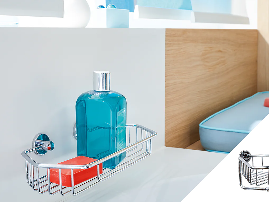 A metal shower caddy is mounted on a white wall using tesa tape. It holds a blue bottle and an orange soap bar. In the background, theres a white shelf, wooden paneling, and blue cushions. An inset image shows a close-up of the empty caddy. (This text has been generated by AI)