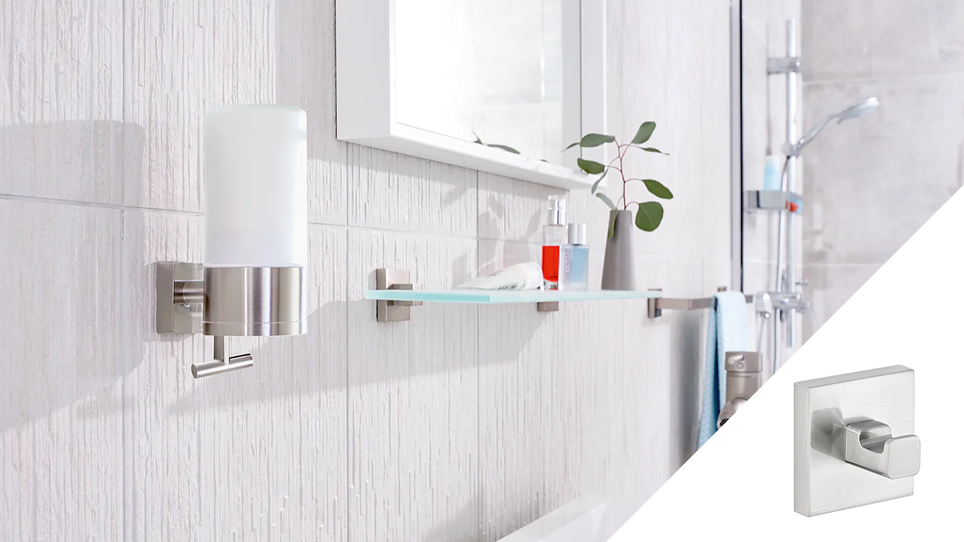 Wall-mounted bathroom accessories are shown, including a soap dispenser with a metal finish and a glass shelf holding a small bottle and a plant. A square wall hook is inset in the image, featuring a simple modern design, all secured using tesa tape. (This text has been generated by AI)