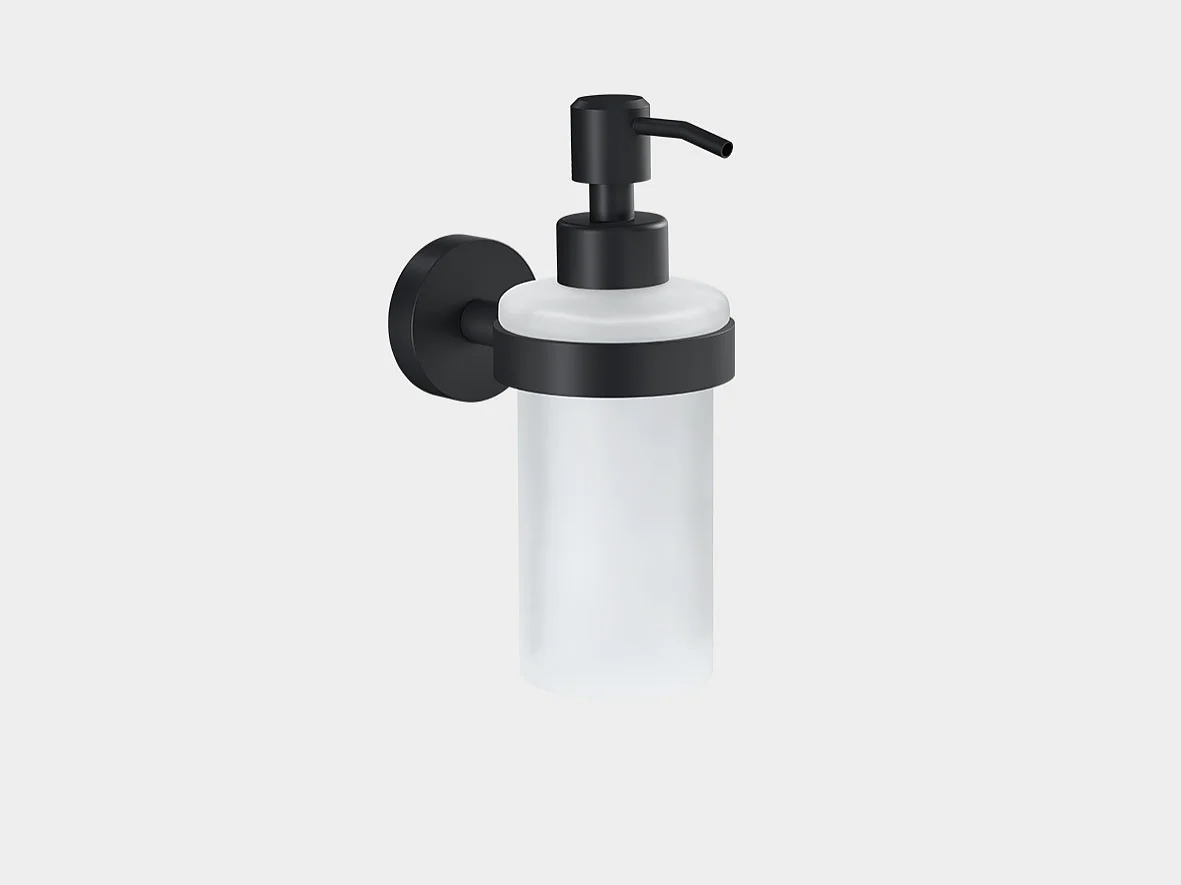 Wall-mounted soap dispenser with a frosted glass container and black metal pump and holder. The dispenser is secured using tesa tape against a plain white background. (This text has been generated by AI)