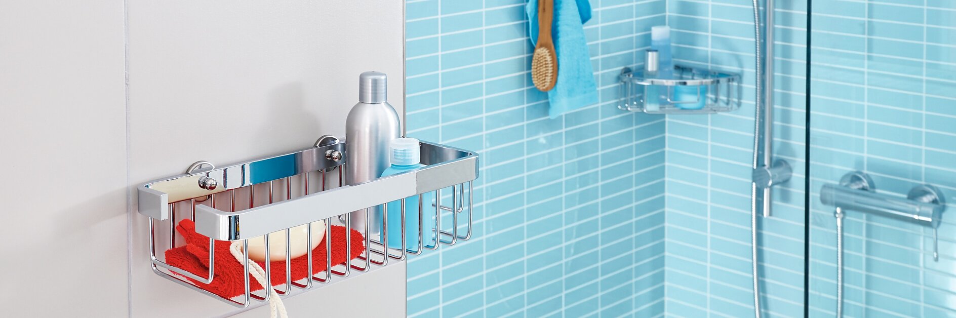 A modern bathroom with light blue tiles features a wall-mounted metal shower caddy holding a red cloth, a soap bar, and a bottle. A showerhead with an adjustable arm is on the right, along with a hanging washcloth and broom nearby. The installation is secured using tesa tape for added stability. (This text has been generated by AI)