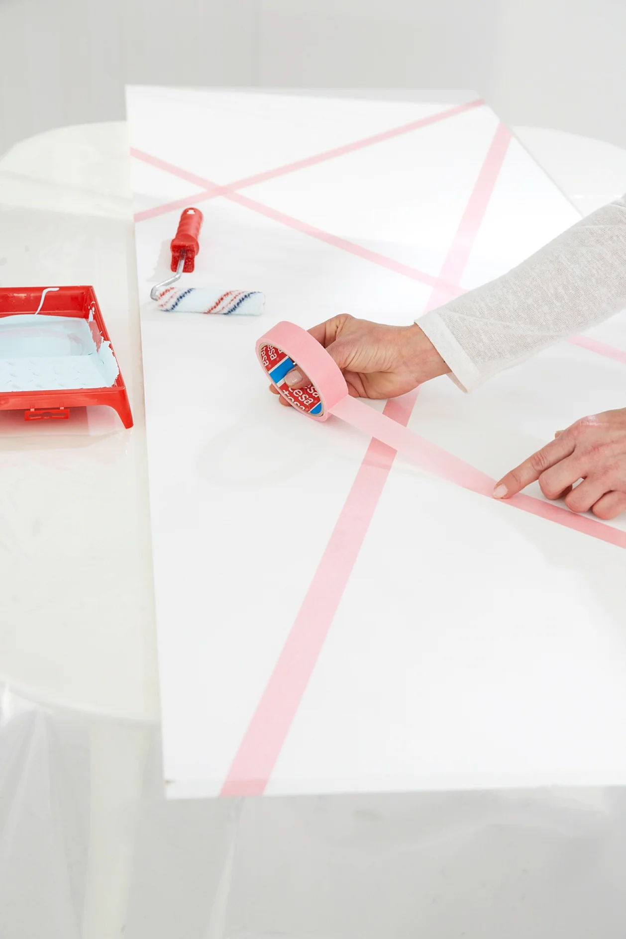 tesa trendpapier 9 / Idee 6: Magnetwand / Schritt 1 Die Platte mehrfach mit Magnetfarbe grundieren, trocknen lassen und weiß streichen. Das Maler-Krepp kreuz und quer auf die Platte kleben und gut andrücken.