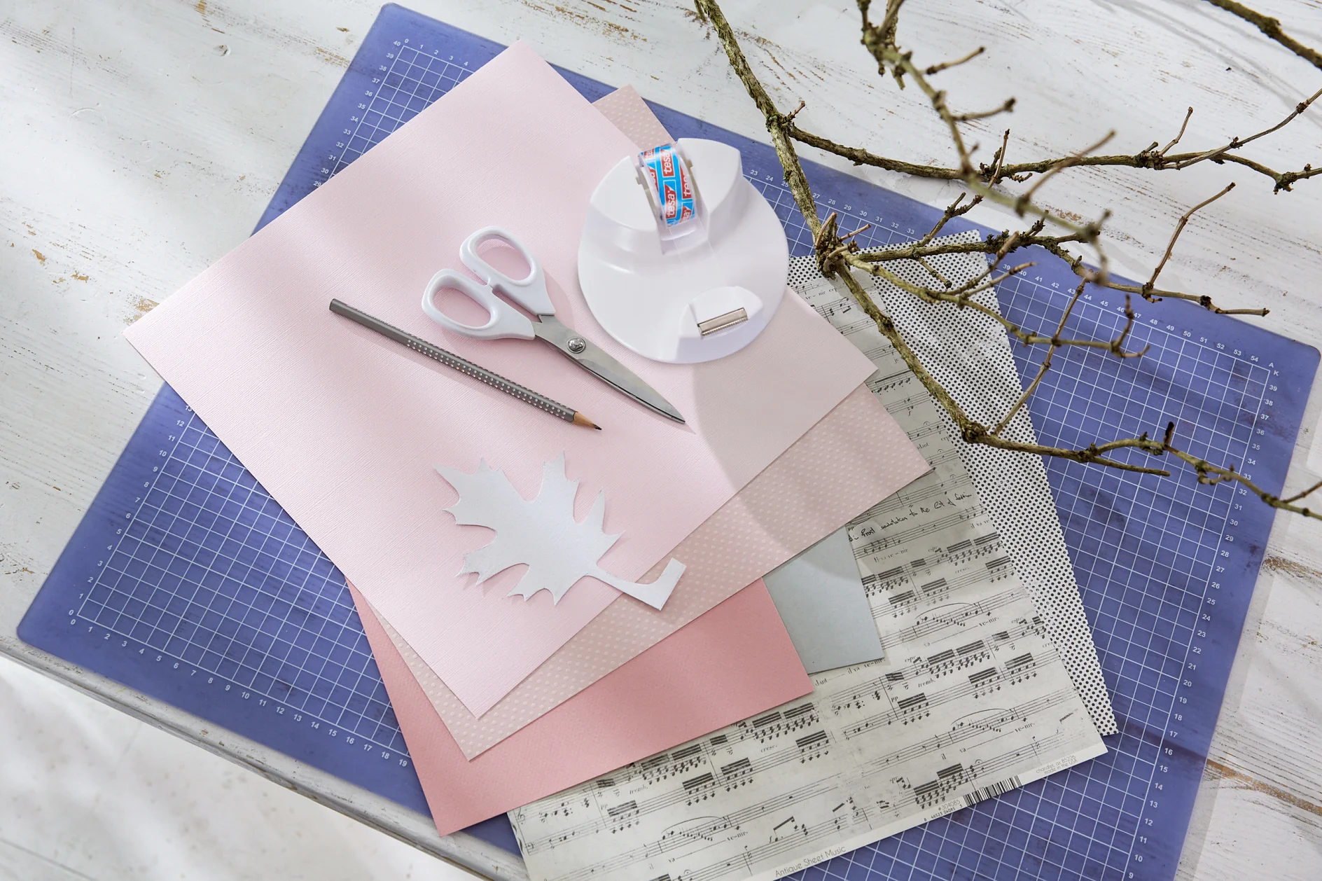 tesa trendpapier 10 / Idee 3: Blätter Ast / Schritt 1 Das brauchen wir: Festes Papier für die Schablone, Schablonenvorlage, graue und rosafarbene Papiere (uni und gemustert), Ast, Schere, Bleistift, tesafilm® kristall-klar
