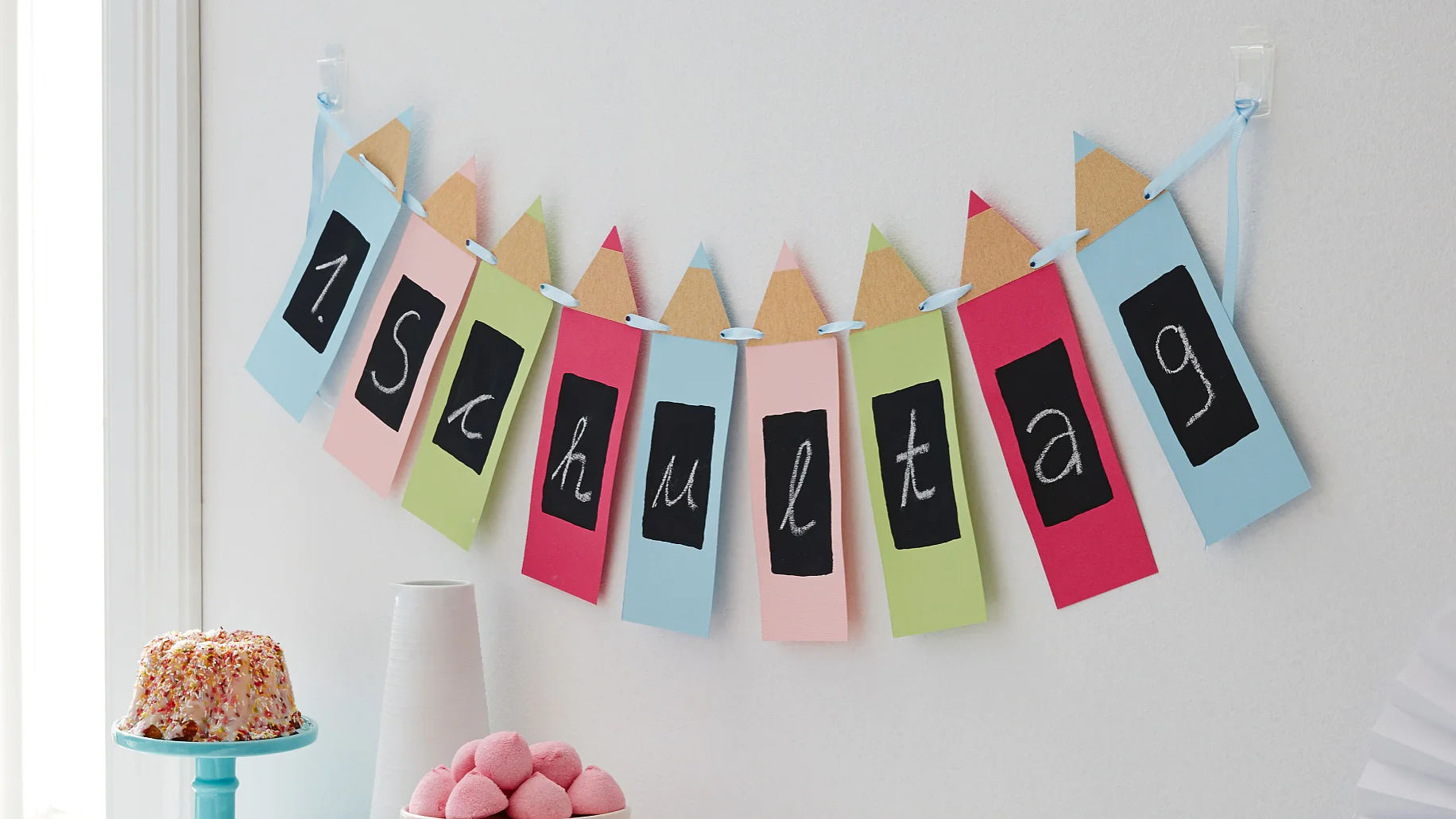 Kreidezeichen: An so einem besonderen Tag wird sogar die Wand geschmückt: Die Buntstiftgirlande zur Einschulung macht ganz unmissverständlich klar, was heute gefeiert wird! Sie ist schnell selbst gemacht und kann immer wieder neu beschriftet werden, weil die Schreibfläche ganz passend mit Tafellack angemalt ist.