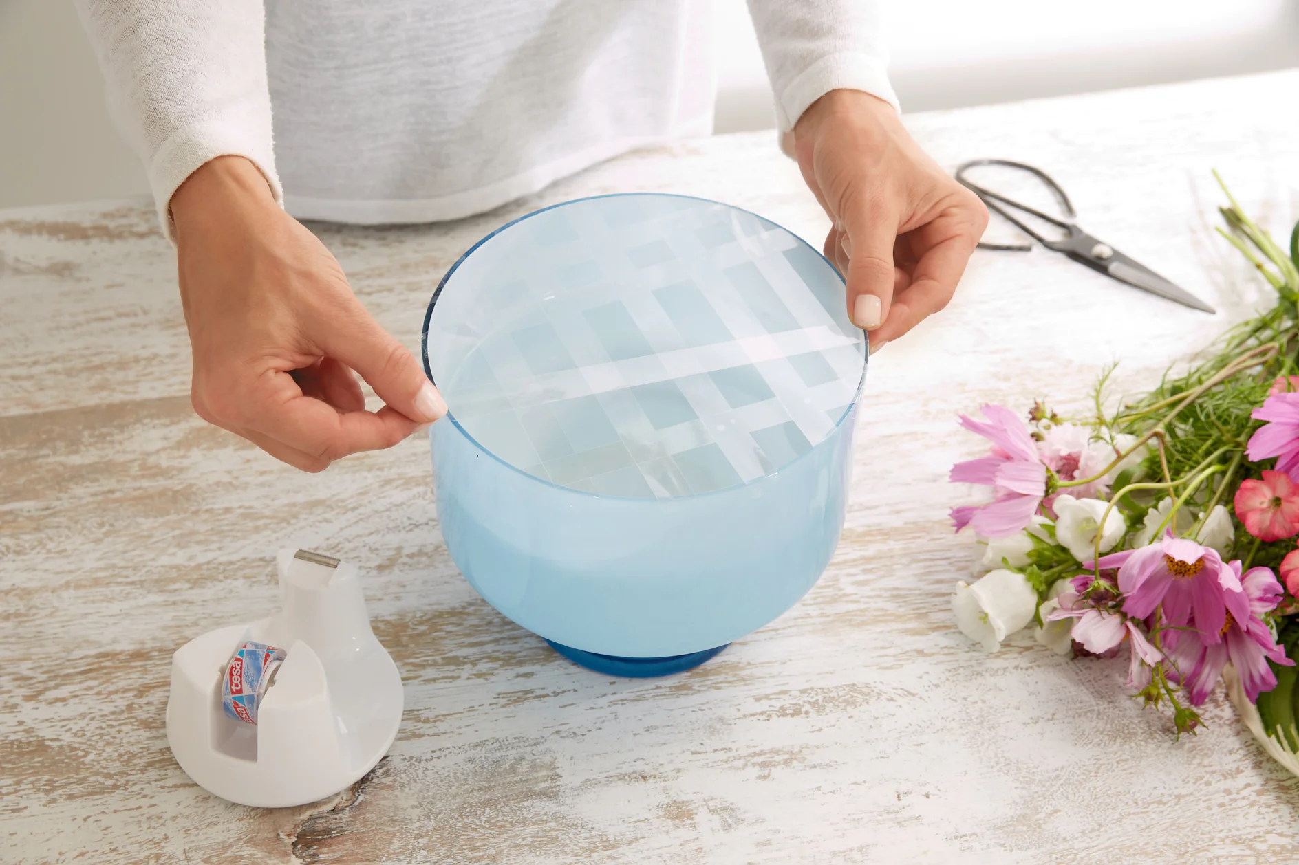 Mit tesafilm® wird ein Gitter auf die Vasenöffnung geklebt.