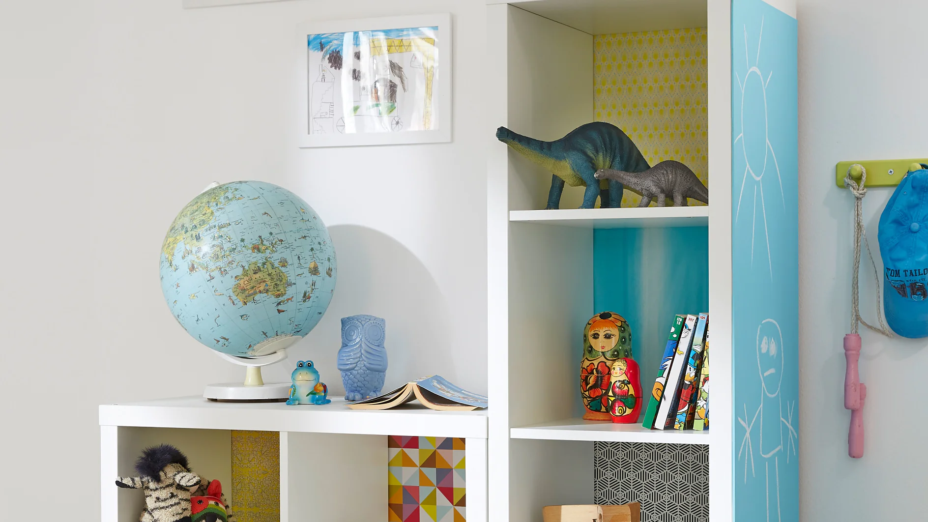 Die große, mit Powerbond® verklebte Tafel an der Seite lädt zu Schreib- oder Malversuchen ein, und jedes Regalfach hat seinen eigenen bunt gemusterten Hintergrund – wenn das kein tolles Kindermöbel ist!