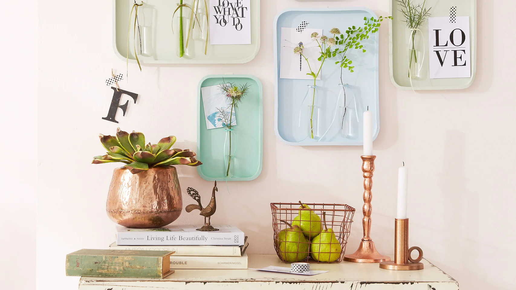 Das Wandtableau besteht aus Tabletts, an denen Reagenzgläser für die Blumen befestigt sind. Witzig: Postkarten und Bilder werden mit gemustertem tesa® Deco Tape befestigt, das sehr dekorativ aussieht, sich aber auch ruck, zuck wieder entfernen lässt.