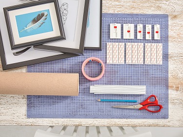 Das brauchen wir: Viele unterschiedliche Bilderrahmen mit Federmotiven, Bleistift, Schere, Packpapier, Zollstock, tesa® Malerband TAPETEN 25 m x 38 mm, tesa® Verstellbarer Klebenagel für Tapeten und Putz, 1 kg oder 2 kg – je nach Gewicht des Rahmens