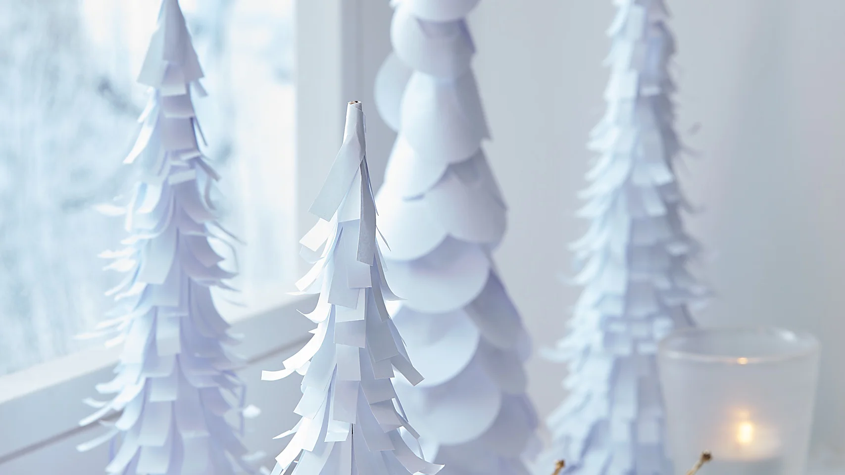 Viele weiße Bäume auf der Fensterbank bringen Winterstimmung ins Haus, auch wenn es draußen gar nicht schneit. Sie werden aus schlichtem weißen Papier und Pappkegeln gebastelt – je mehr, desto besser!