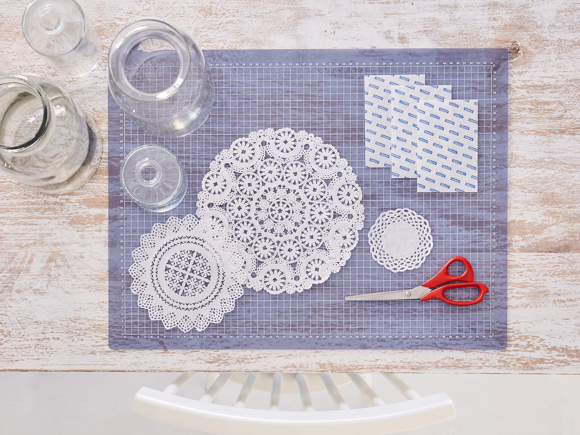 Das brauchen wir: Unterschiedliche Glasvasen, Schere, Tortenspitze aus Papier in unterschiedlichen Größen und Mustern, tesa® TACK Transparente Doppelseitige Klebepads