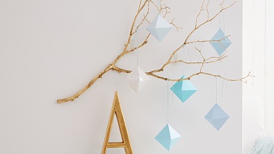 Statt Bild: Warum nicht einmal einen Ast mit grafischen Prismen an die Wand hängen? Sie werden aus unterschiedlich farbigem Papier  von Hand gefaltet. Hat man den Dreh einmal raus, geht’s ganz fix. Unauffälligen Halt bekommt das Kunstwerk durch tesa Powerstrips® Transparent DECO Haken LARGE.