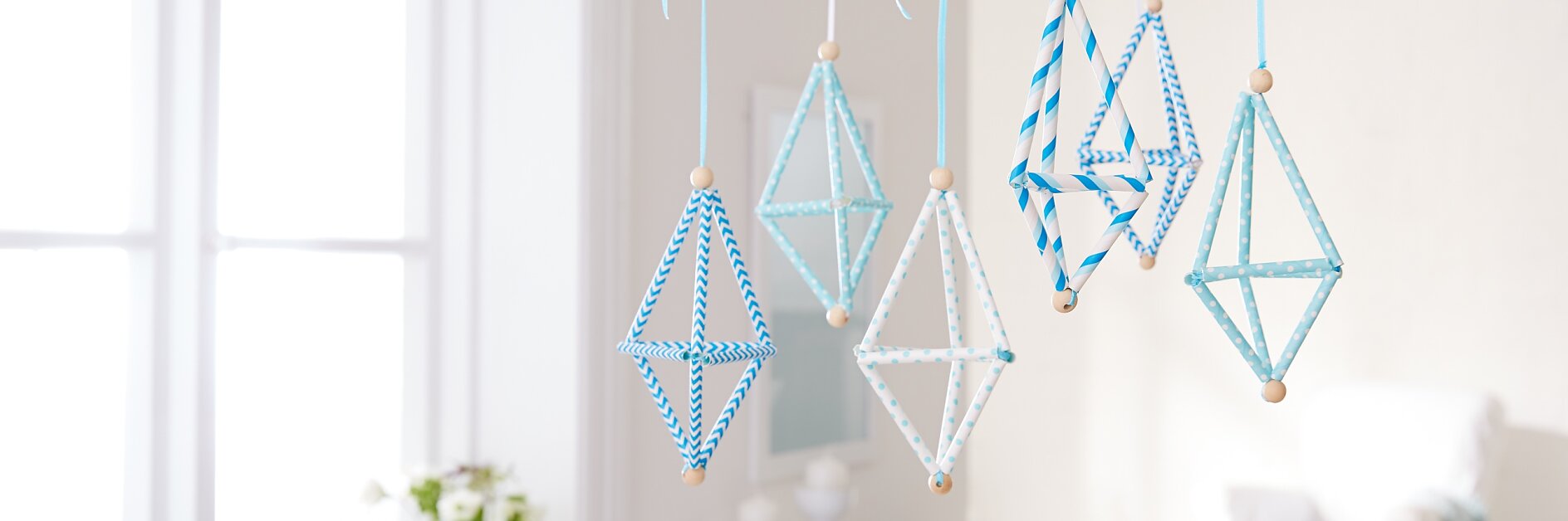Kaum zu glauben, aber diese kleinen Flugobjekte werden aus Strohhalmen mit etwas Geschick selbst gefädelt. Also einfach mal ausprobieren und das aparte Kunstwerk dann mithilfe eines Powerstrip® Transparent DECO Hakens LARGE an der Decke befestigen.