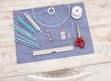 Das brauchen wir: Metallring für Lampenschirme ø 30 cm (Bastelbedarf), 3 mm breites Band (pro Element 1,5 m + ca. 3 m zum Aufhängen je nach Deckenhöhe), Papierstrohhalme, kleine Holzperlen ø 12 mm, Lineal, Schere, lange Nadel, tesa Powerstrips® Transparent DECO Haken LARGE