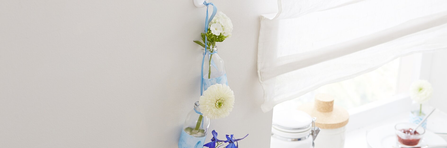 Jede Blume ist ein Kunstwerk – deshalb bekommt auch jede Blüte ihre eigene, individuell mit Papier verzierte Vase. Sie sind alle durch ein Band verbunden. Sicherer Aufhänger ist ein tesa Powerstrips® Haken LARGE Oval, der bis zu zwei Kilogramm tragen kann.