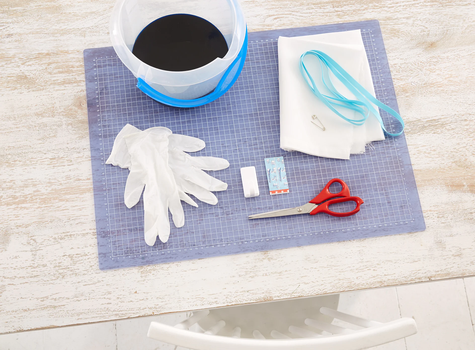 tesa trendpapier 26 / Idee 12: Küchengardine / Schritt 1 Das brauchen wir: Eimer, Textilfarbe, Handschuhe, weißen halbtransparenten Stoff aus Naturfasern (gewünschte Höhe der Gardine + 4 cm x Breite), Band (Breite der Gardine + 60 cm) Sicherheitsnadel, Schere, Nähmaschine, tesa Powerstrips® Haken LARGE Classic