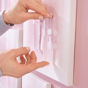 Bild auf den Klebenagel hängen und die gefüllten Reagenzglasvasen an den Klettpunkten aufhängen. Vasen mit einzelnen Blüten dekorieren.