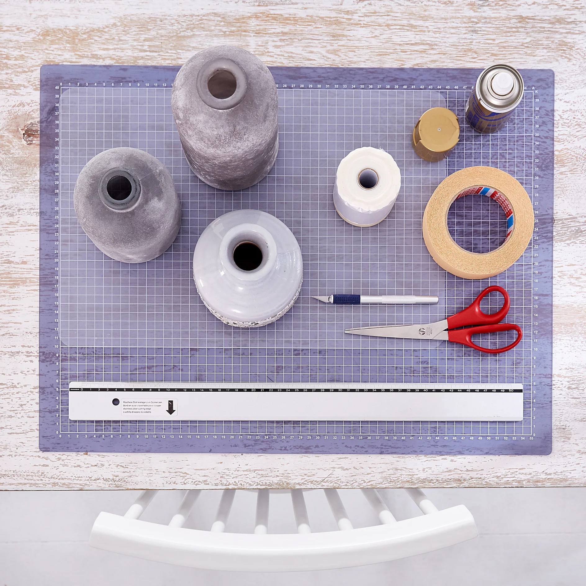 tesa trendpapier 28 / Idee 5: Vasen / Schritt 1 Das brauchen wir: Unterschiedliche geradlinige graue Vasen, Cutter, Schere, Lineal, größere Plastikunterlage z. B. einfaches Tischset, Sprühlack Gold, tesa Easy Cover® Premium M, tesa® Malerband für Kurven 25 m x 38 mm
Zeitvorgabe: 10 Minuten + ca. 2 Stunden Trocknungszeit