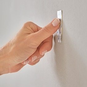 Powerstrip an der gewünschten Stelle auf die Wand kleben und 5 Sekunden an mehreren Punkten fest andrücken.