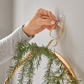 Holzring golden lackieren, trocknen lassen. Oben mit Zweigen umwickeln und ein Band zum Aufhängen befestigen. Daran an die Wand hängen und die Päckchen mit dem goldenen Garn daran drapieren.