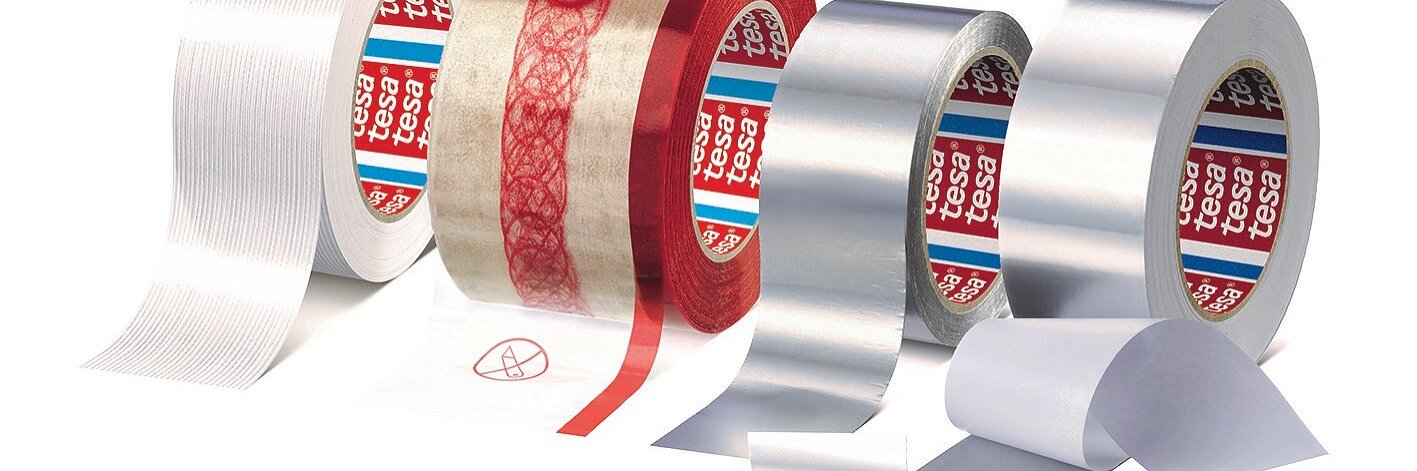 Ausgestellt werden verschiedene Rollen Tesa-Klebeband, darunter weißes, transparentes mit rotem Muster, silbernes und ein schlichtes transparentes. Sie sind teilweise abgerollt, um ihre Textur und ihr Aussehen zu zeigen. (This text has been generated by AI)
