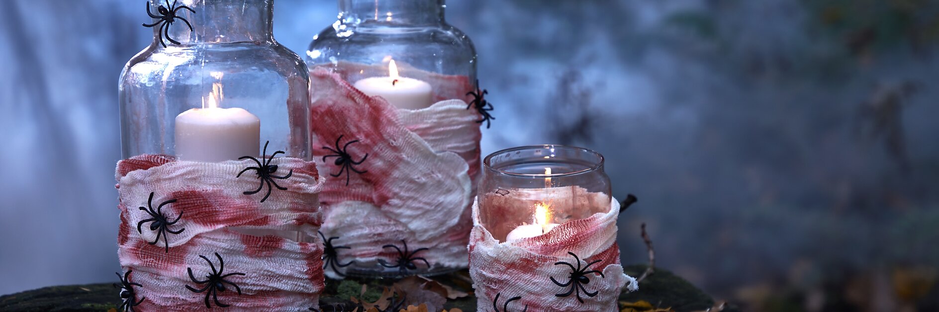 Achtung: Hier herrscht Ekelalarm! Aber genau darum geht es ja an Halloween. Deshalb verzieren wir die Glaswindlichter mit (kunst-)blutverschmierten Mullbinden und vielen ekligen Spinnen!
