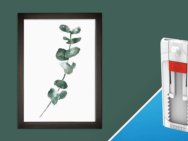 Ein minimalistischer gerahmter botanischer Druck mit grünen Blättern auf der linken Seite. Auf der rechten Seite ist ein weißer selbstklebender Wandhaken mit einer roten Lasche auf blauem Hintergrund zu sehen, der mit Tesa-Klebeband befestigt ist. Das Bild ist diagonal geteilt und zeigt beide Artikel nebeneinander. (This text has been generated by AI)