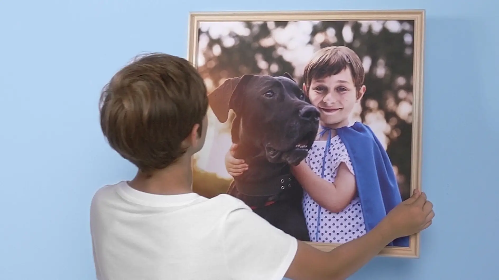 A boy looking at a picture of himself and his dog.